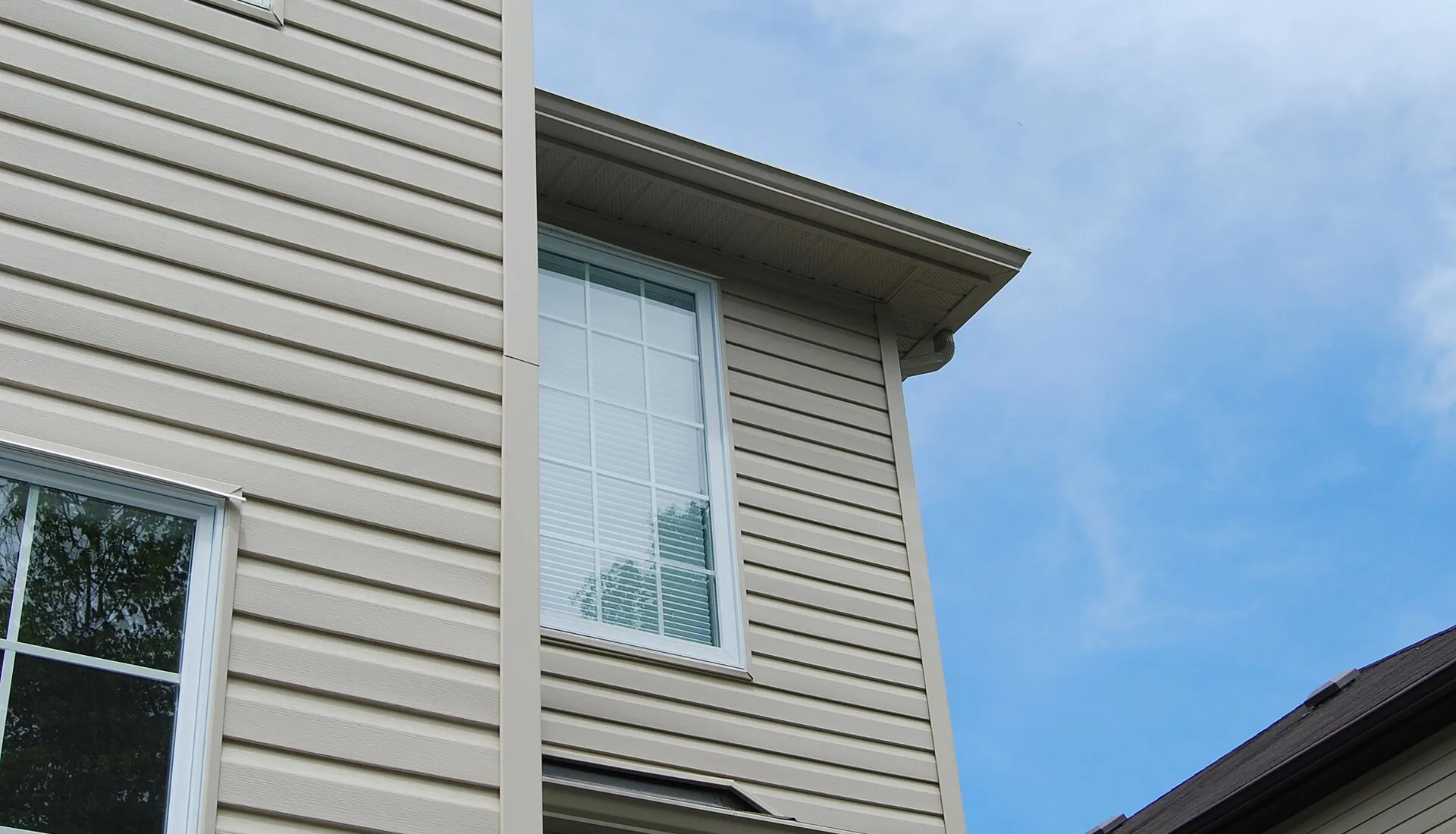 Beige vinyl siding with white trim and windows